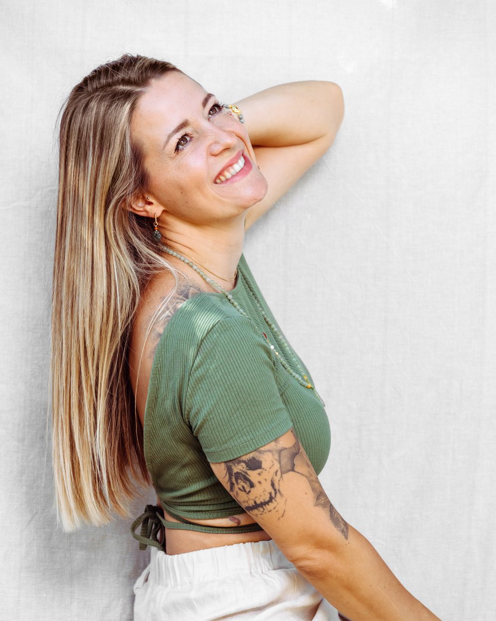 Julia May lacht, an eine helle Leinenwand gelehnt